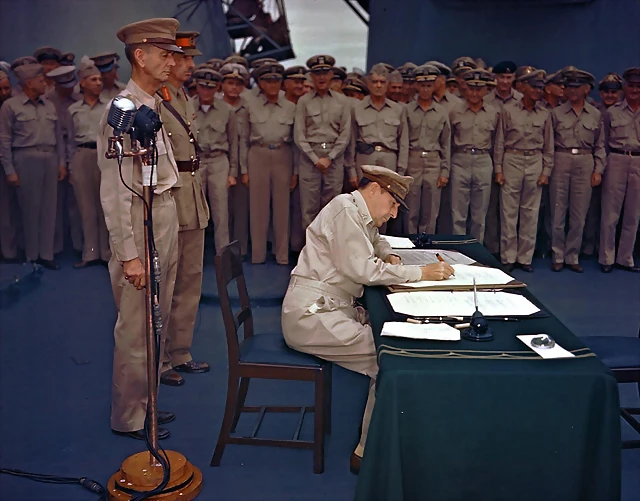 September 2, 1945 Gen. Douglas MacArthur signs the Japanese surrender documents aboard the USS Missouri in Tokyo Bay. Lt. Gen. Jonathan Wainwright, left foreground, who surrendered Bataan to the Japanese, and