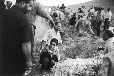 2002 Rodeado de gente y soldados que caban fosas para las vctimas de un terremoto, un nio sujeta los pantalones de su padre muerto