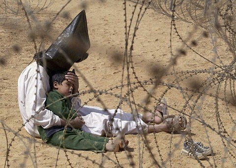2003 Un iraqu reconforta a su hijo en un centro de prisioneros de An Najaf, Irak, durante la guerra.