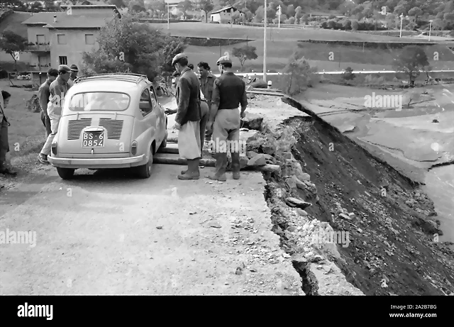 los-hombres-dejan-un-fiat-600-coche-en-carretera-rota-esta-carretera-fue-destruida-por-la-tormenta-en-italia-la-tormenta-devasto-las-ciudades-de-loveno-valcamonica-y-boario-terme-en-la-provincia-de-brescia-en-lombardia-2a2b7bg los-hombres-dejan-un-fiat-600-coche-en-carretera-rota-esta-carretera-fue-destruida-por-la-tormenta-en-italia-la-tormenta-devasto-las-ciudades-de-loveno-valcamonica-y-boario-terme-en-la-provincia-de-brescia-en-lombardia-2a2b7bg