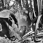 Un marine americano ayudando a salir de un agujero a una mujer de una de las islas del Pacfico que sufrieron en la WWII