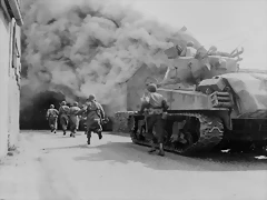Miembros del 55 Batallón de Infanteria y un tanque del 22 Batallón entrando en una calle en llamas en Wernberg. Alemania. 1945 Miembros del 55 Batallón de Infanteria y un tanque del 22 Batallón entrando en una calle en llamas en Wernberg. Alemania. 1945