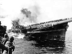 March 19, 1945 The USS Santa Fe lies alongside the heavily listing USS Franklin to provide assistance after the aircraft carrier had been hit and set afire by a single Japanese dive bomber, during the Okinawa