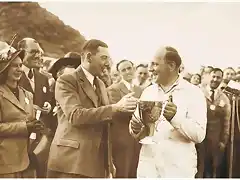 Dennis Perry, a director of the Kemsley Press, hands the winner's trophy for Goodwood's Formula One race to Reg Parnell